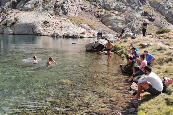 Un grupo de excursionistas tomando un baño, actividad no permitida, en un lago de alta montaña en el Parque Natural del Alt Pirineu