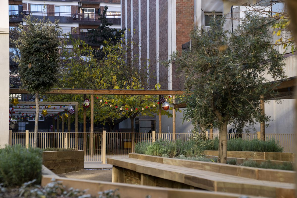 Área con jardineras en la escuela Els Llorers y unas pérgolas de madera al fondo. Foto: Mariona Gil.